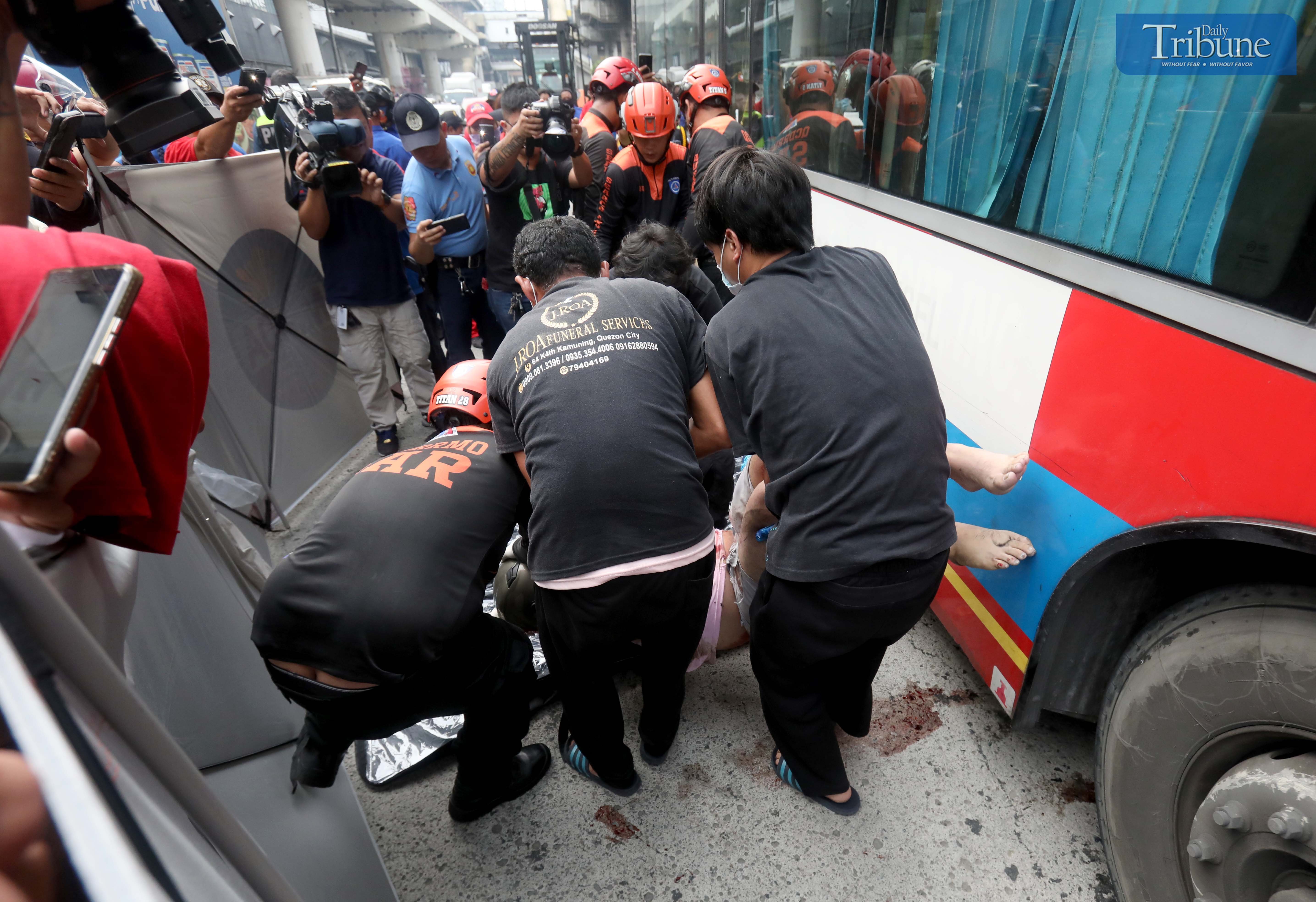Personnel from the Quezon City Disaster Risk Reduction and Management Office removes the remains of a motorcycle rider who was dragged by a passenger bus along North Edsa in Quezon City on Monday. Photo by Analy Labor